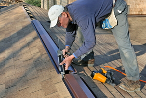 A man works on a ridge vent.