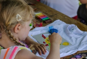 A young girl painting a t-shirt.