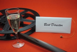 A movie reel and an Oscar award envelope against a red background.