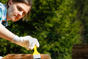 Woman brushing on wood chemical stripper
