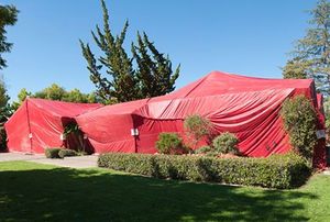 A home covered in a red termite fumigation tent.