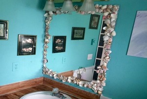 A bathroom mirror surrounded by seashells.