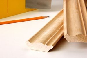 Two pieces of pine wood molding sitting on a table beside a pencil.