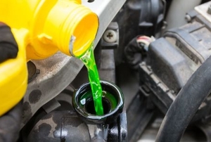 pouring green coolant into a car radiator