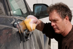 a person rubbing a sponge on a car door