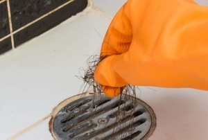 A woman gets hair out a drain.