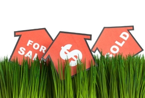 A close-up of grass with red house sings on top of it.