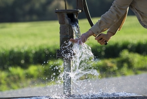 A person using a well pump.