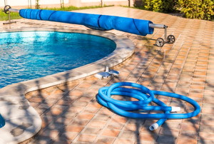 a backyard pool with hose laying on the patio