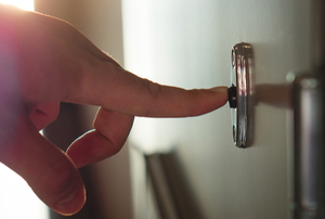 finger pressing doorbell in bright hallway