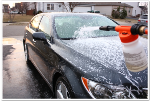 person spraying car wash onto a car