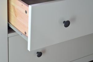 White-front drawer with black knob slightly ajar.