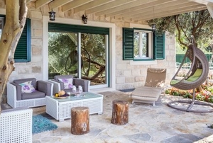 a stone patio under a wood roof with furniture and plants