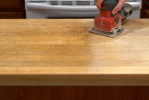 hand with power sander refinishing wood tabletop