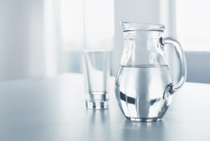 a glass next to a pitcher of water