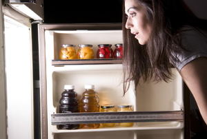 woman looking into an open refrigerator