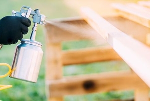 a man spray painting a fence