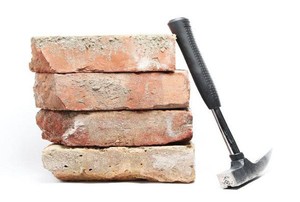 A brick hammer laying against a stack of bricks.