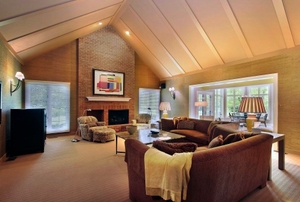 A family room with carpet and couches in neutral tones.