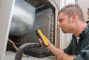 A professional repairman inspecting the coils of an AC unit.