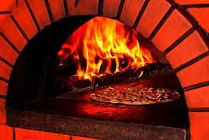 A pizza baking in a brick oven.