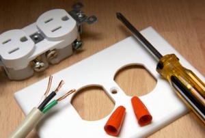 A disassembled electrical outlet with wiring, a screwdriver, face plate, caps, the outlet itself.