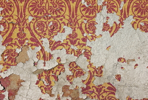Old wallpaper peeling off a wall in pieces.