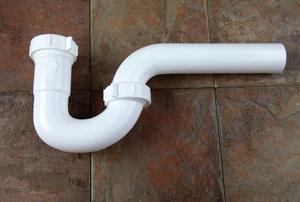 A PVC P-trap on a tile floor.