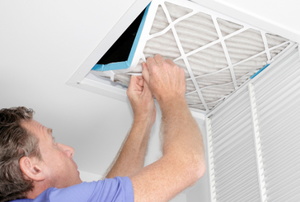 man adjusting filter in large air vent