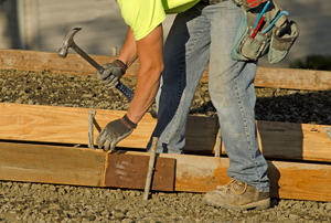 A worker putting down concrete forms for a sidewalk.