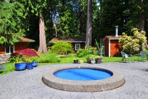 A backyard patio with a small hot tub set in the ground.