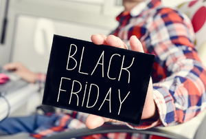 A person wearing a plaid shirt and holding a sign that says "black friday." 