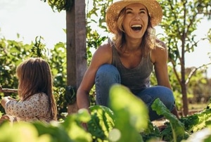 laughing woman with girl in vegetable patch