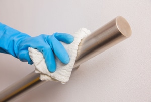 gloved hand wiping a metal handrail
