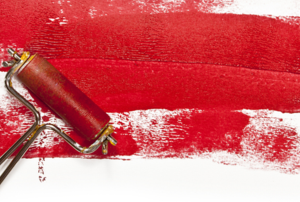 Rolling red paint onto a wall