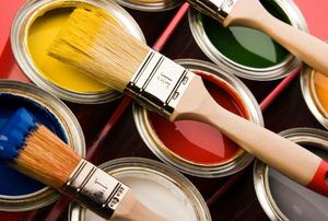 a variety of open paint cans with paint brushes on top
