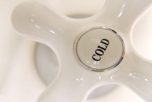 A vintage-style white faucet head that reads "cold".