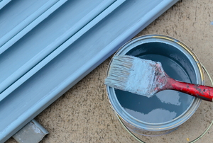 paint on exterior surface drying near can and brush