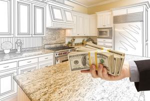 A hand holding cash in front of a kitchen remodel.