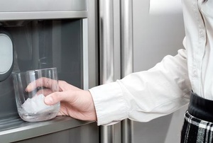 A woman uses an ice maker.
