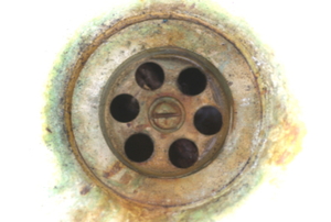 An old sink drain with residue around the edge.
