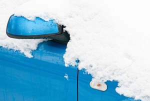A blue car engulfed in snow.