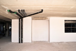 A basement with several pipes traveling from floor to ceiling.