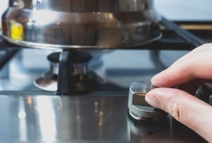 hand on knob of unlit stove