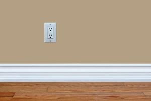White baseboards against a tan wall and wood flooring.