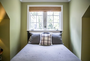Bed in front of window with Roman blind