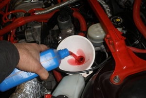 A hand pouring transmission fluid into a funnel.
