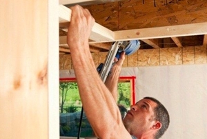 A man installing basement ceiling frames.