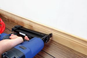 A man installs baseboards.