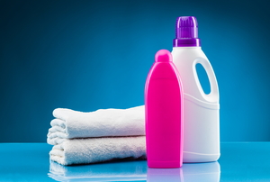 bottles of laundry detergents in front of folded towels